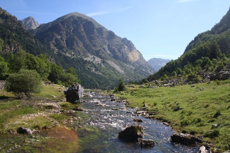 Río de aguas cristalinas entre praderas y montañas en el Parque Nacional de Aigüestortes, en el Pirineo de Lleida