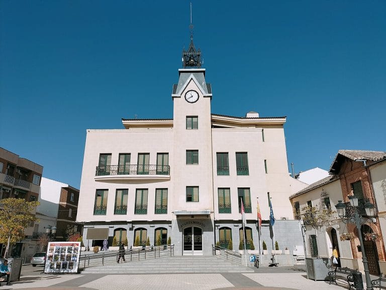 Fachada del Ayuntamiento de Calzada de Calatrava con su torre del reloj y banderas en la entrada