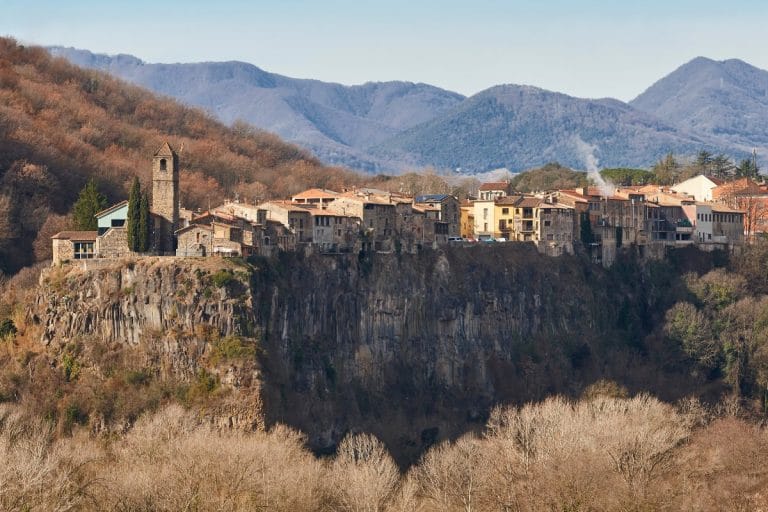 Iglesia de Castellfollit de la Roca y casas asomadas al acantilado basáltico, en la comarca de la Garrotxa, Girona.