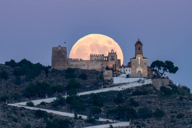 Vista del castillo de Cullera y la iglesia de los Santos Juanes con la luna llena al atardecer