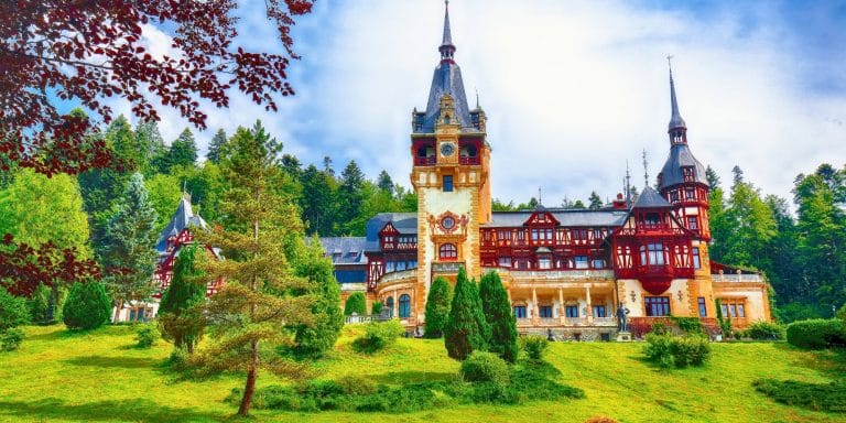 Castillo de Peleș en Sinaia rodeado de montañas y bosques en Rumanía