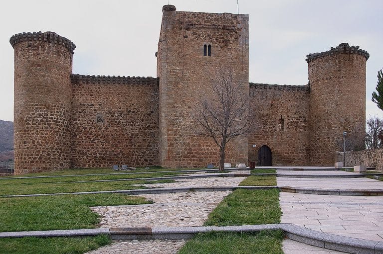 Castillo de Valdecorneja en El Barco de Ávila, fortaleza medieval de piedra rodeada de jardines y caminos empedrados.