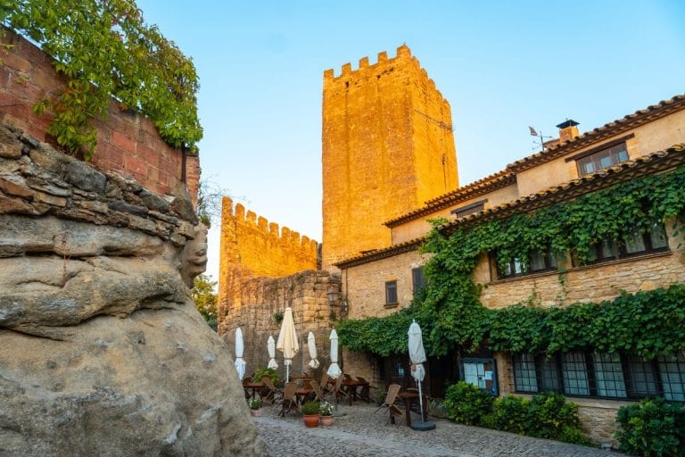Texto ALT SEO: Castillo medieval de Peratallada y terraza con sillas al atardecer
