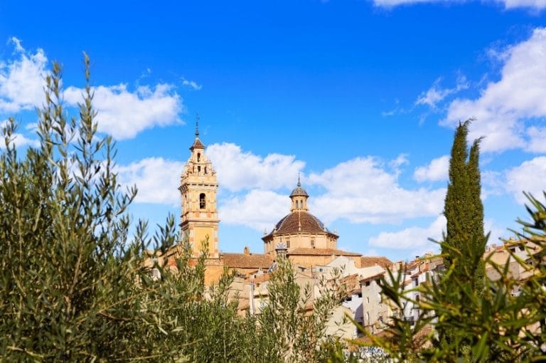 Campanario e iglesia con cúpula en Chelva, Valencia, vistos entre olivos