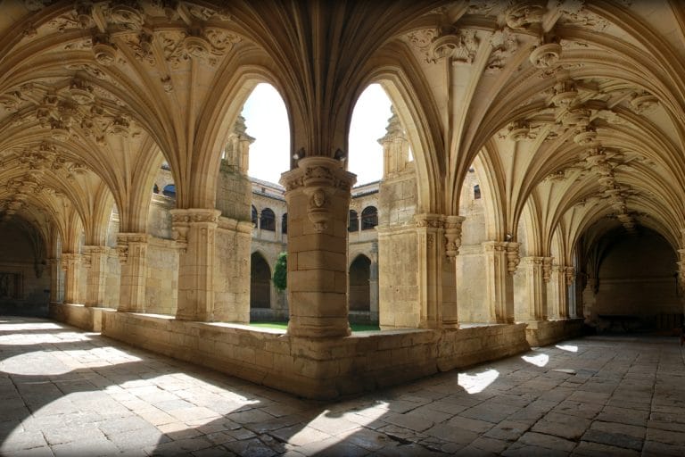 Claustro gótico del monasterio en Carrión de los Condes, con bóvedas de crucería y arcos apuntados iluminados por la luz natural.