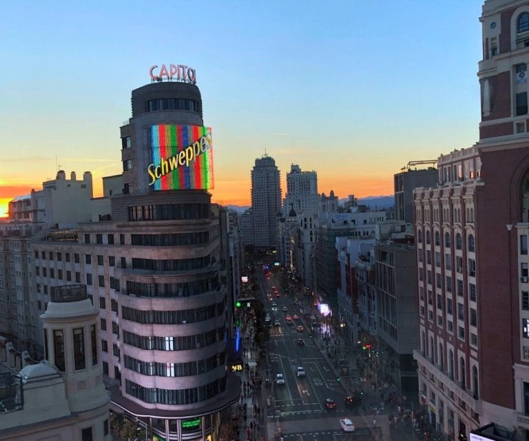 Vista del Edificio Capitol en la Gran Vía de Madrid al atardecer con el cartel luminoso de Schweppes