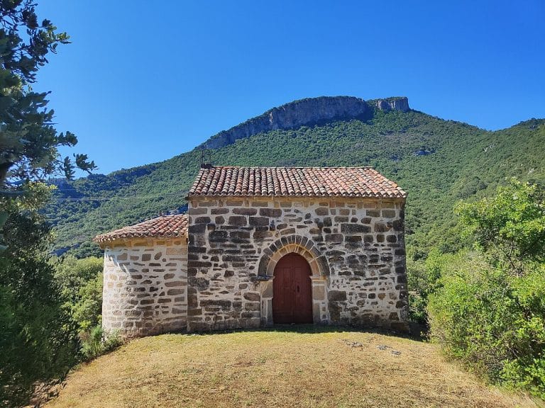 Ermita de Quijera rodeada de vegetación en Sobrón, provincia de Burgos, con el monte al fondo.