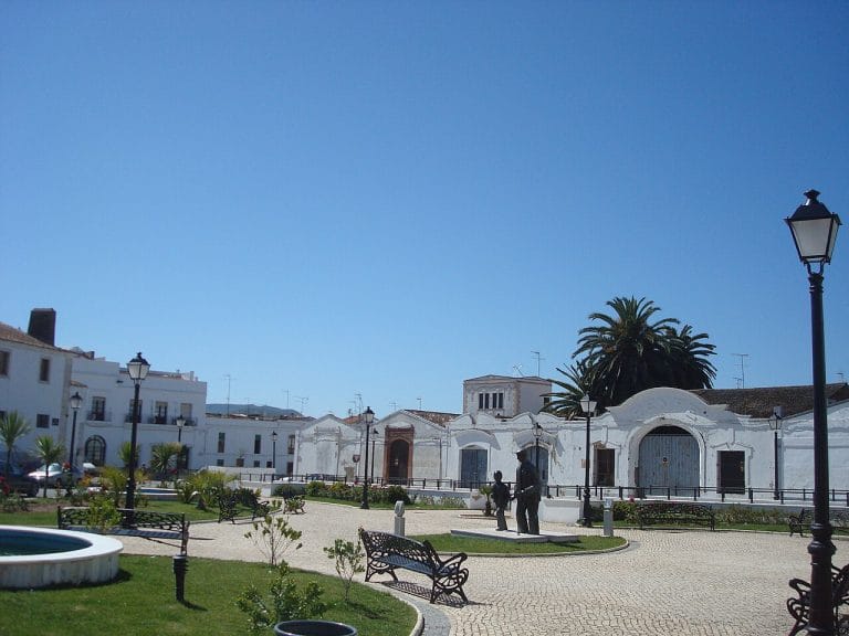Antigua estación de tren de Olivenza en Badajoz, con fachadas blancas y jardín con esculturas