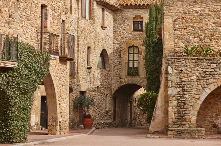 Fachadas de piedra y calle adoquinada en la Plaça Jaume I de Monells, Girona.