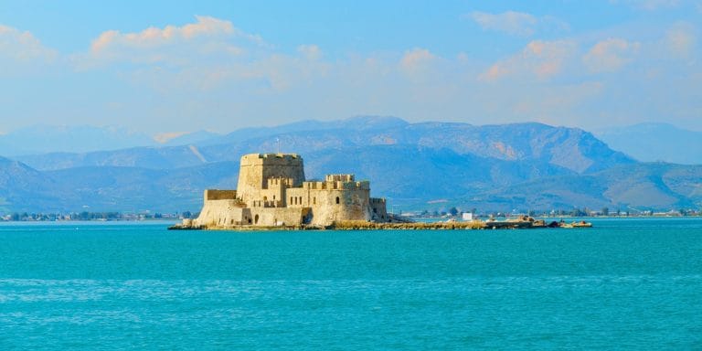 Vista de la fortaleza Bourtzi en Nafplio, Grecia, rodeada por el mar con montañas al fondo