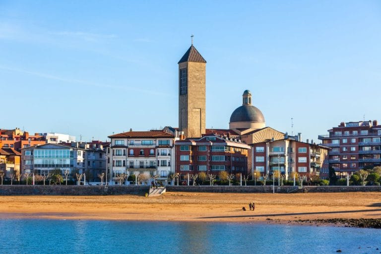 Iglesia de Las Arenas en Getxo vista desde la playa, con edificios residenciales frente al mar