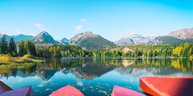 Botes rojos en el lago Strbske Pleso en Eslovaquia con montañas y bosques reflejados en el agua