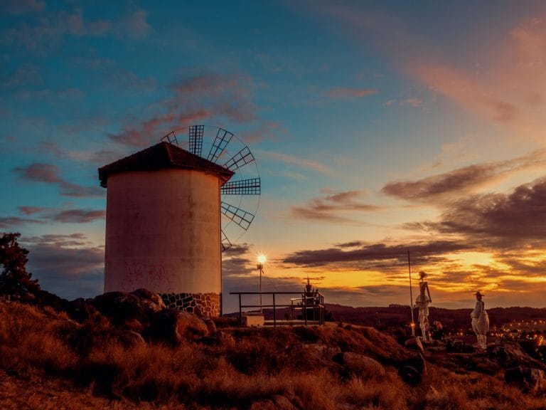 Molino de viento en Consuegra con esculturas de Don Quijote y Sancho Panza al atardecer, en la provincia de Toledo