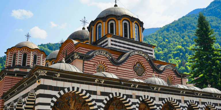 Monasterio de Rila en Bulgaria con sus cúpulas y fachadas decoradas rodeado de montañas