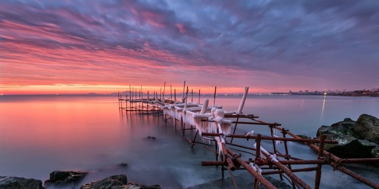 Muelle cubierto de hielo en Burgas sobre el mar durante una puesta de sol