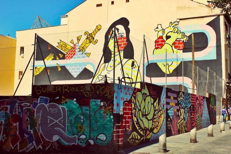 Mural de arte urbano en Lavapiés, Madrid, con grafitis coloridos y figuras decorando una fachada
