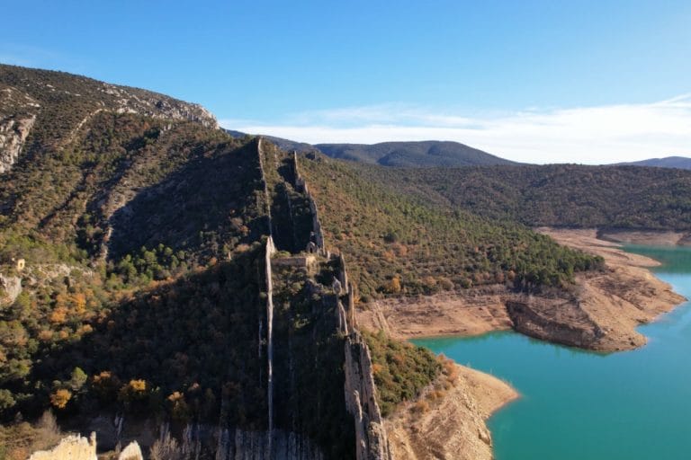 Vista aérea de la Muralla de Finestres, una espectacular formación rocosa vertical que se eleva junto a las aguas turquesas del embalse de Canelles, rodeada de montañas