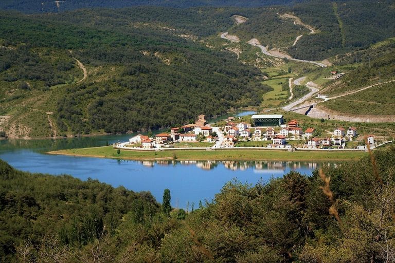 Vista panorámica del pueblo de Nagore junto al embalse, rodeado de montañas y bosque en Navarra