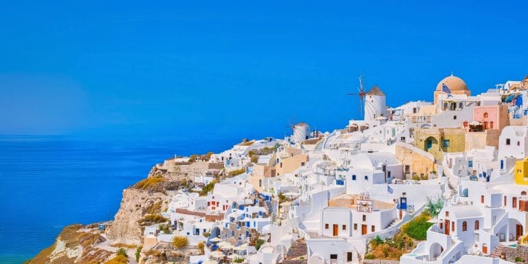 Vista panorámica de Oia en Santorini, Grecia, con casas blancas y molinos junto al mar Egeo
