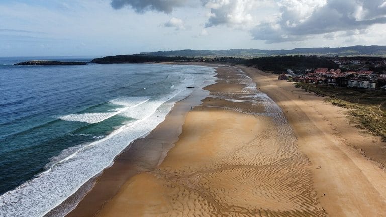 Vista aérea de la playa de Somo en Ribamontán al Mar, Cantabria, con olas perfectas para surf y zona urbana al fondo