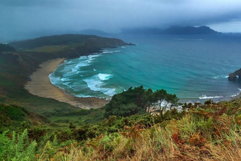 Vista panorámica de la playa de Ortigueira y los acantilados del norte de Galicia en un día nublado.