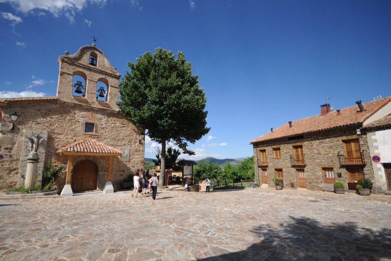 Plaza principal de La Hiruela con la iglesia de piedra y casas tradicionales en la Sierra Norte de Madrid