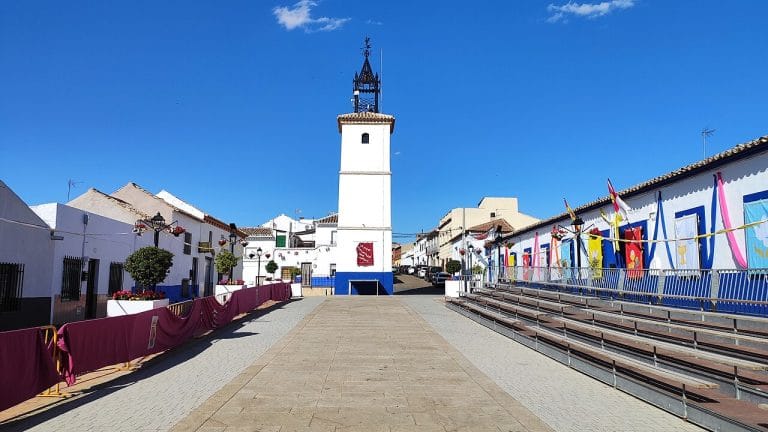Plaza Ramón y Cajal de Camuñas decorada para el Corpus Christi, con la torre del reloj al fondo y gradas para el evento festivo