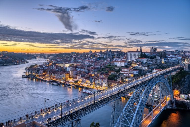 Vista panorámica de Oporto al anochecer con el puente de Luis I iluminado sobre el río Duero, Portugal