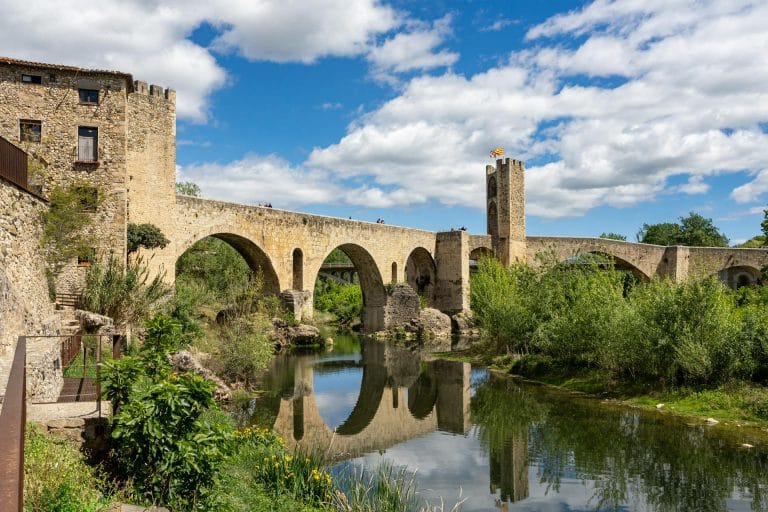 Vista lateral del puente medieval de Besalú reflejado en el río Fluvià, en la comarca de la Garrotxa, Girona.