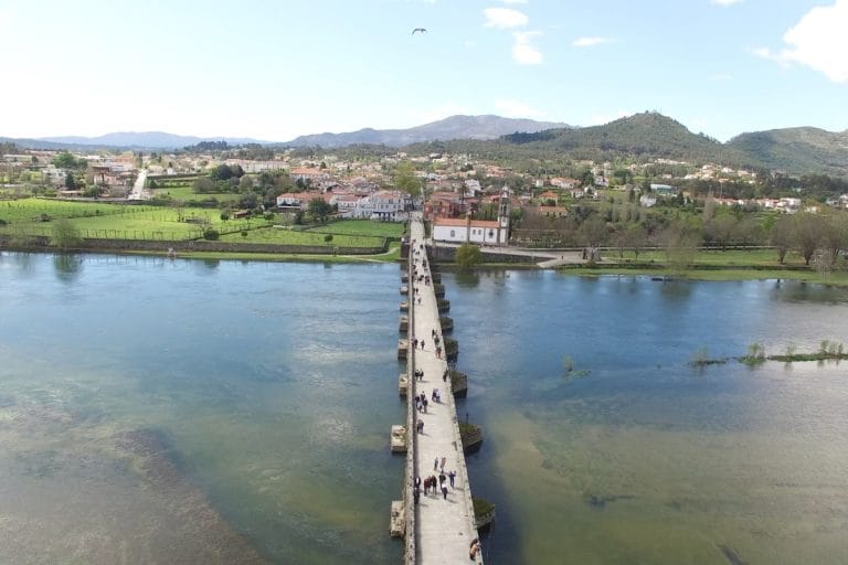 Vista aérea del puente romano de Ponte de Lima sobre el río Lima, con peregrinos cruzando en dirección al casco histórico, Portugal