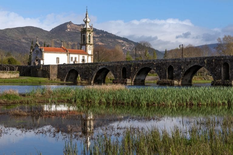Puente romano sobre el río Lima y la Iglesia de Santo António da Torre Velha en Ponte de Lima, Portugal, con montañas al fondo