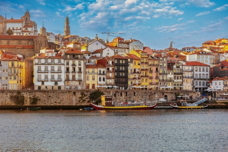 Coloridas fachadas del barrio de la Ribeira en Oporto al atardecer, con barcos tradicionales atracados en el río Duero, Portugal