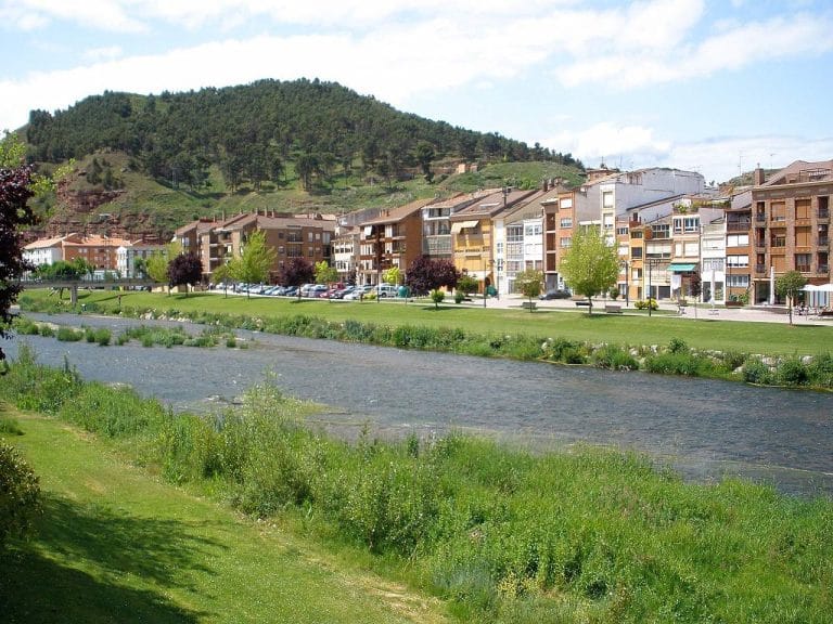 Vista del paseo junto al río Najerilla en Nájera, La Rioja, con casas y montañas al fondo