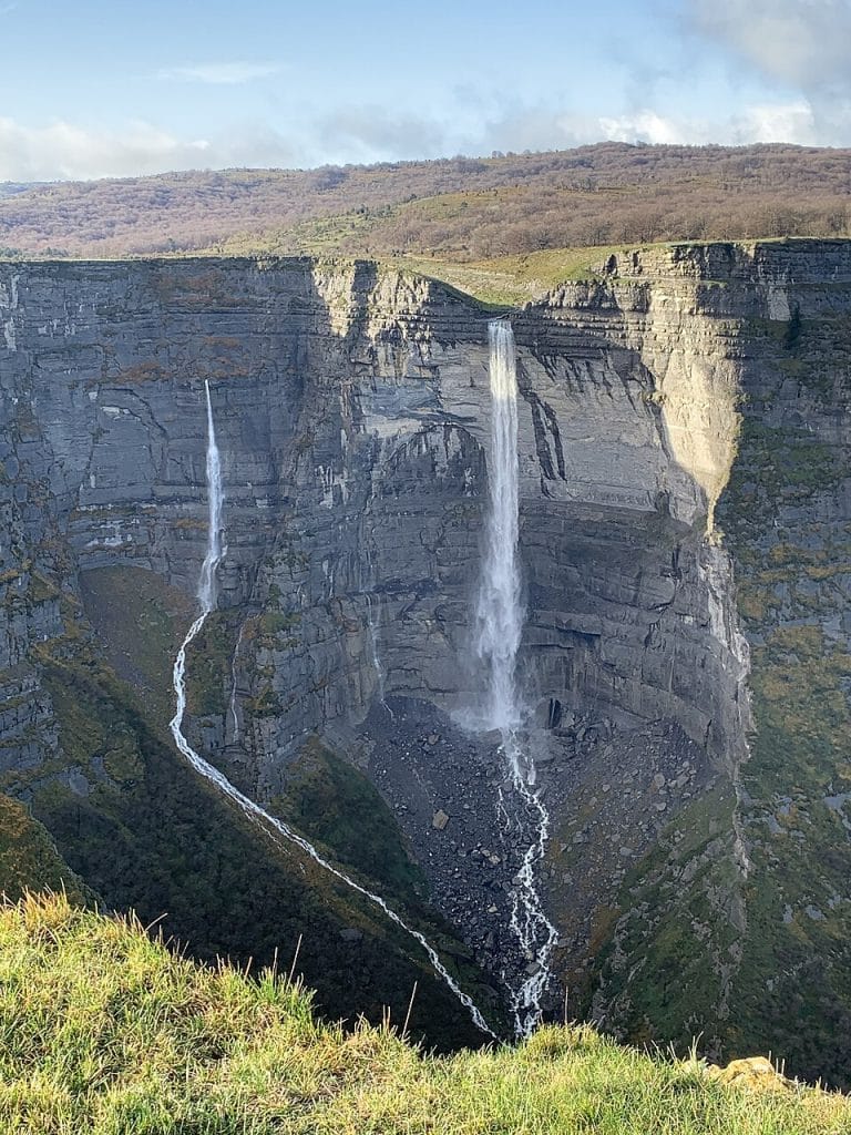 Vista frontal del Salto del Nervión cayendo desde un alto acantilado entre montañas en el límite entre Burgos y Álava