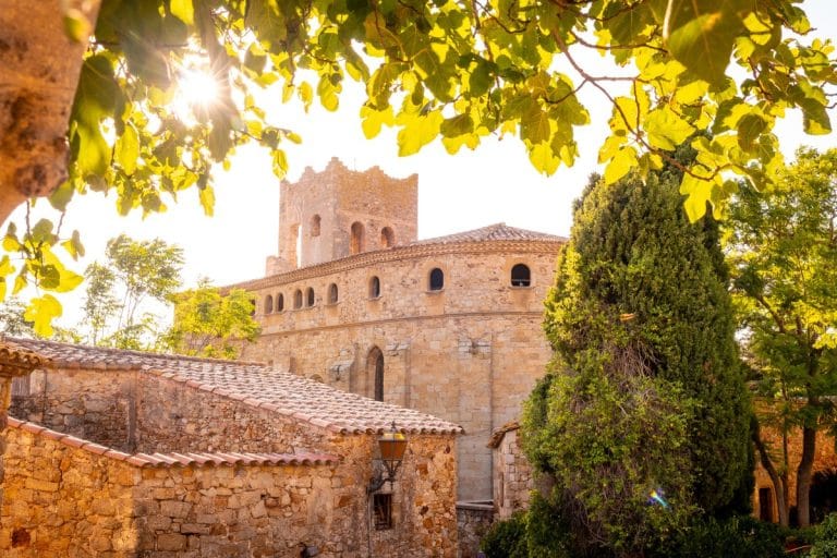 Torre medieval y construcciones de piedra iluminadas por el atardecer en Pals, Girona