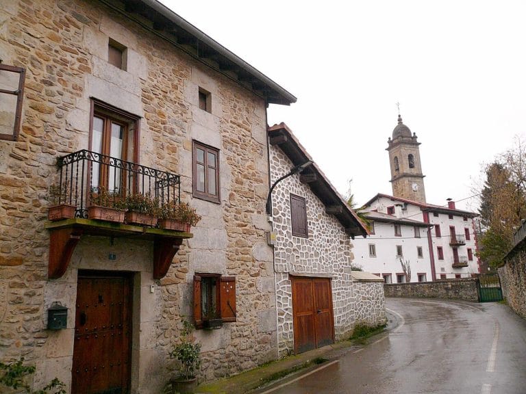 Calle con casas de piedra y vista a la iglesia de San Juan en Ubide, Bizkaia
