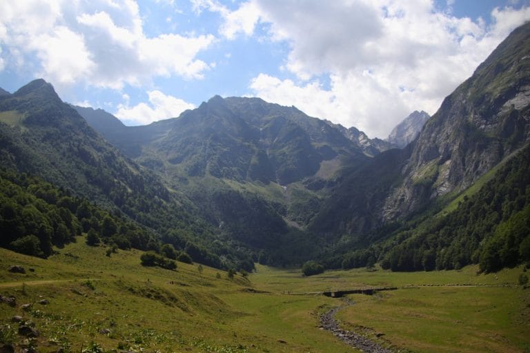 Valle de Arán rodeado de montañas y vegetación con arroyo en primer plano, en los Pirineos de Lleida