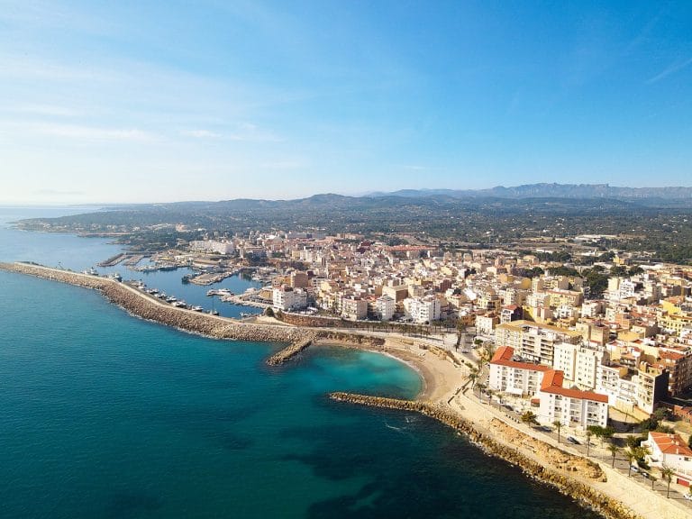 Vista aérea del puerto y el casco urbano de L'Ametlla de Mar con el mar Mediterráneo y la costa al fondo.