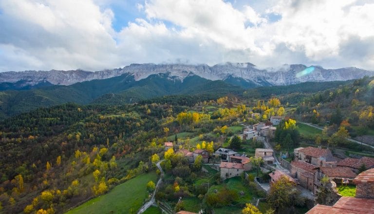 Vista panorámica del Parque Natural del Cadí-Moixeró desde un pueblo del Pirineo catalán rodeado de bosques y casas de piedra