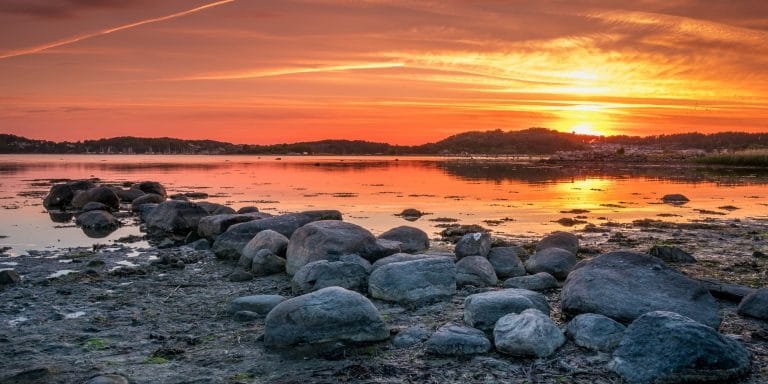Atardecer sobre el mar Báltico cerca de Gotemburgo en Suecia con reflejos anaranjados en el agua y rocas en primer plano