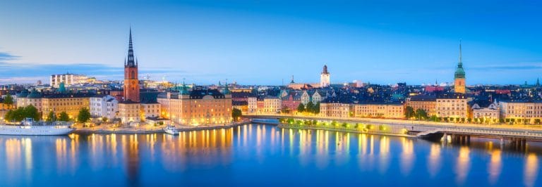 Vista panorámica de Gamla Stan en Estocolmo Suecia al anochecer con edificios iluminados reflejados en el agua