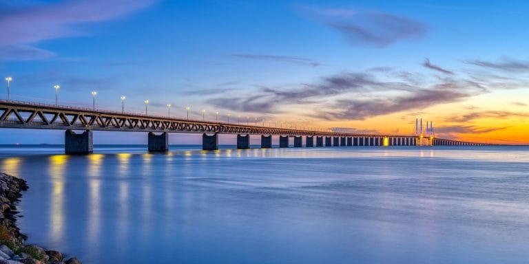 Vista panorámica del puente de Oresund entre Dinamarca y Suecia al atardecer con luces reflejadas en el mar