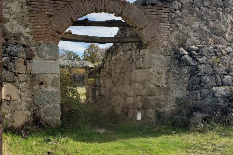 Arco y muros de piedra en ruinas en Villafranca de la Sierra Ávila rodeados de vegetación