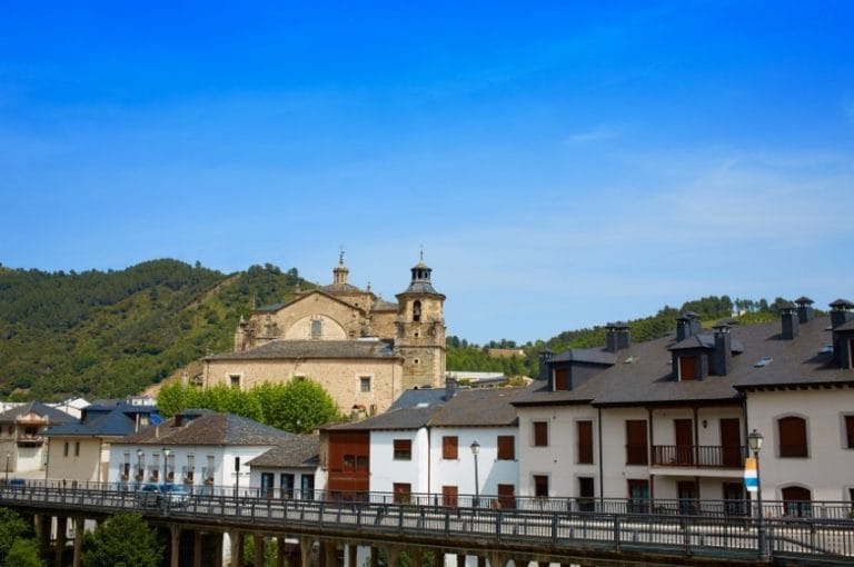 Vista de la Colegiata de Santa María en Villafranca del Bierzo León con casas tradicionales y montañas al fondo