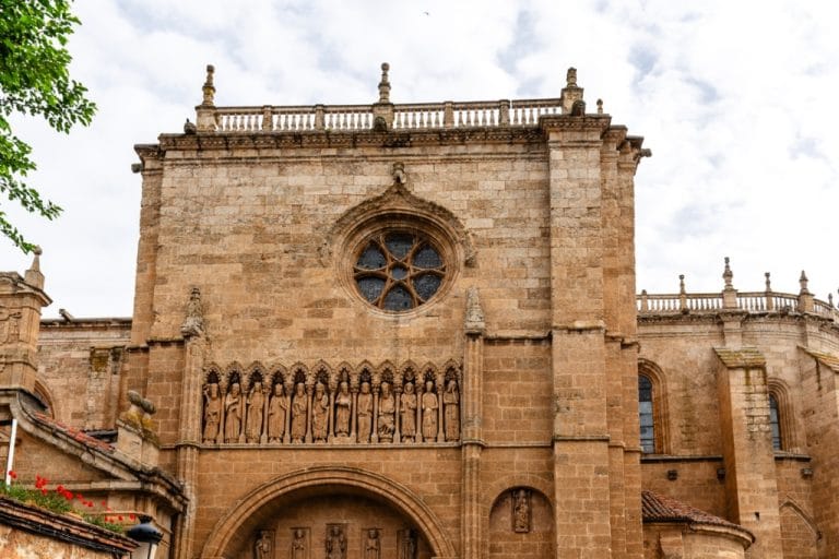 Fachada de la catedral de Ciudad Rodrigo, mostrando la elaborada arquitectura de piedra, el gran rosetón circular y la hilera de estatuas de piedra debajo.