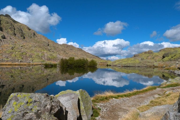 Vista de la Laguna de Gredos en la Sierra de Ávila con montañas y reflejos en el agua.